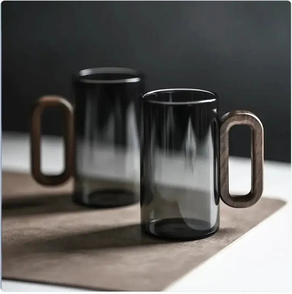 Smoky gray borosilicate beverage cups with wooden handles on a modern table setting.