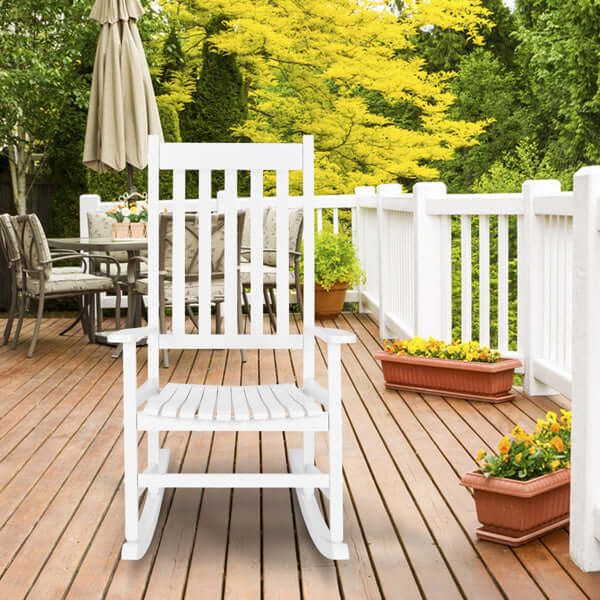 White wooden rocking chair on a sunny deck surrounded by greenery and flower pots, perfect for relaxation.