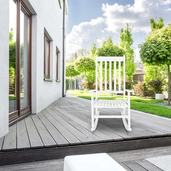 White wooden rocking chair on a wooden deck in a sunny outdoor setting, perfect for relaxing.