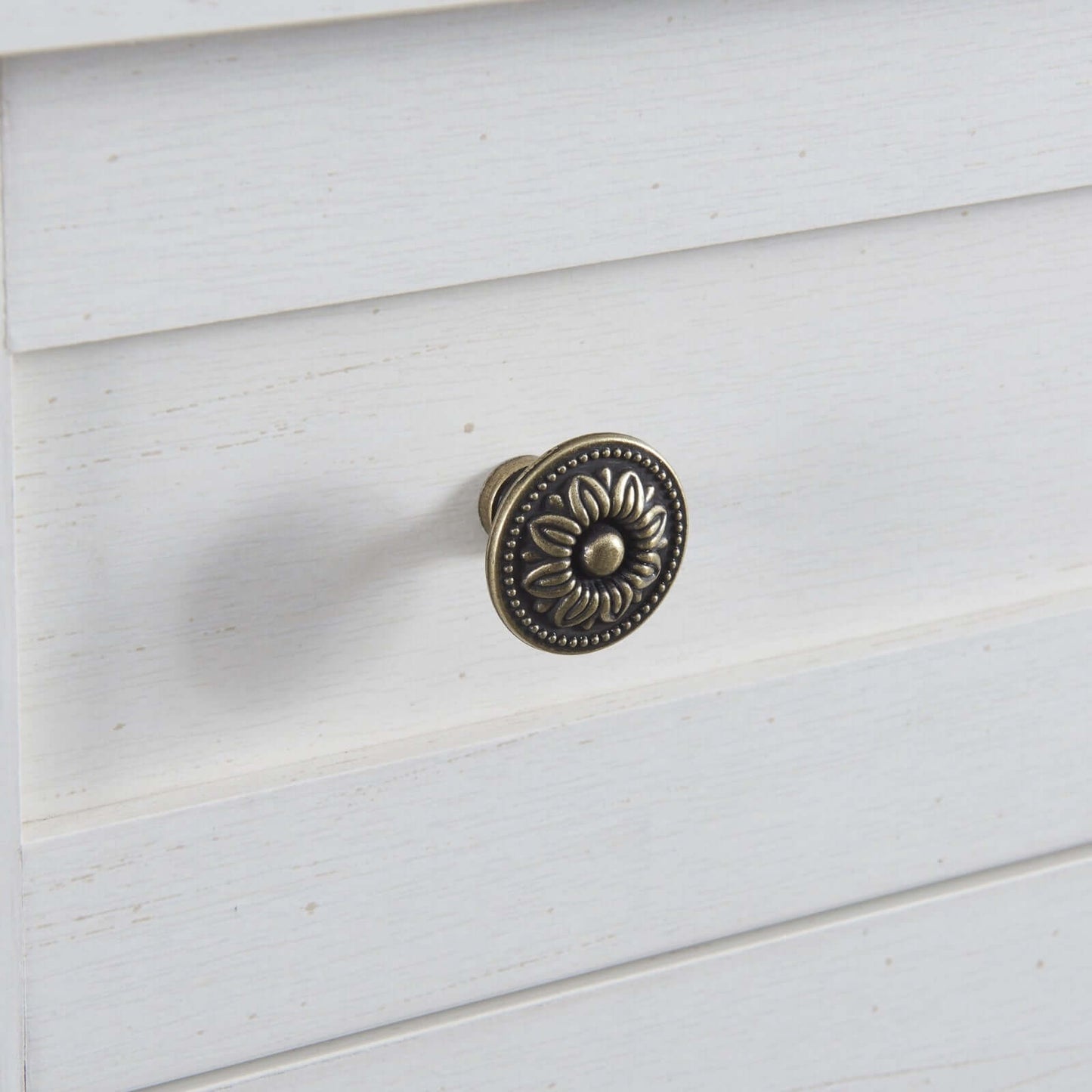 Antique white kitchen sideboard drawer knob with decorative floral design.