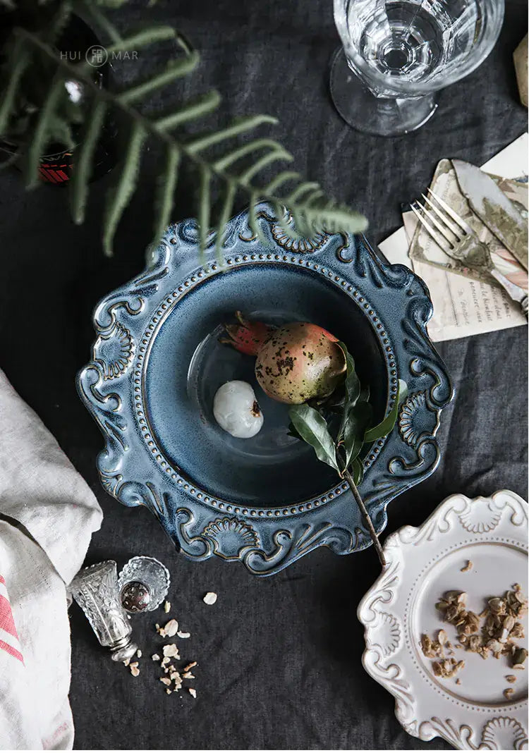 Elegant Baroque-style blue bowl with fruit and leaves, showcasing unique design details and textures.