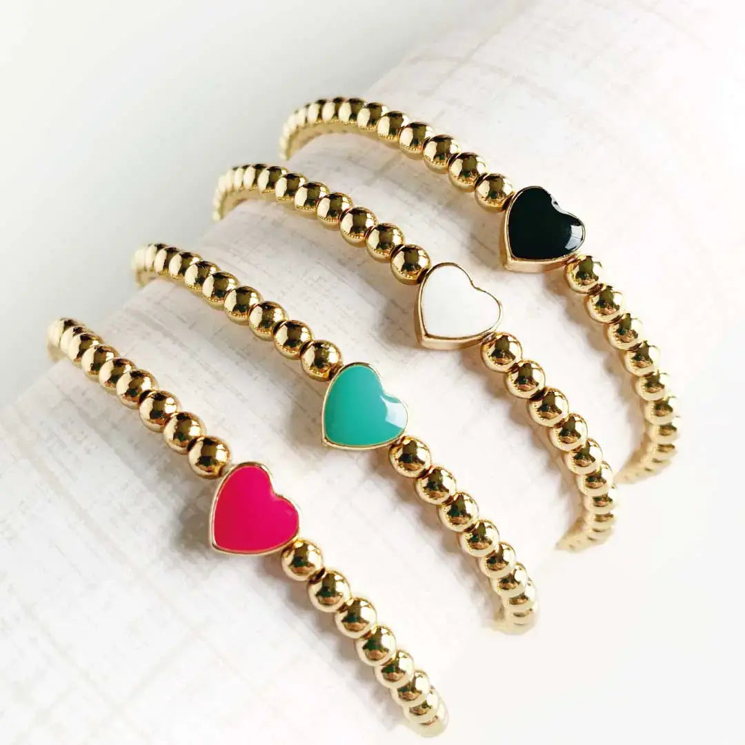 Elegant gold bead bracelets with colorful heart charms, showcasing pink, green, white, and black hearts.