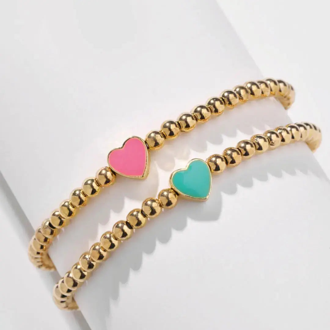 Elegant heart gold bead bracelet with pink and turquoise heart charms, perfect for layering or solo wear.