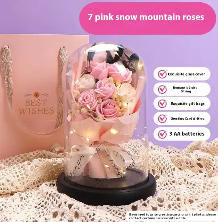 Elegant display of 7 pink snow mountain roses in glass dome with warm LED string lights and gift bag.