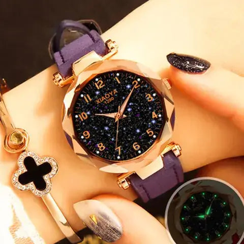Quartz women's watch with luminous starry design, gold accents, and purple strap on wrist.