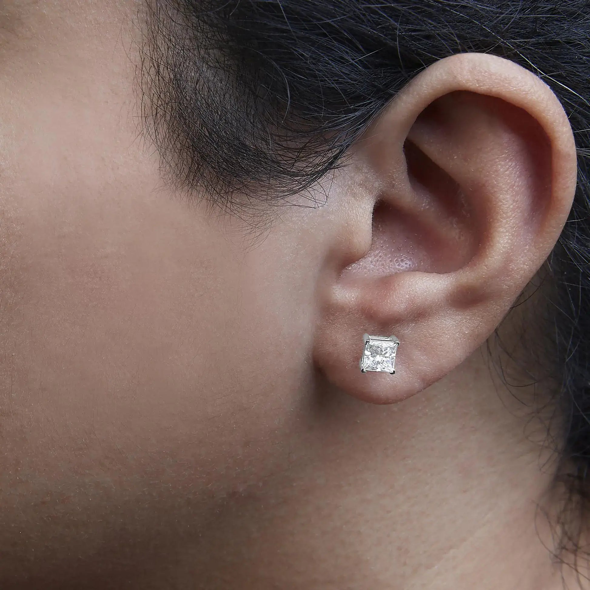 Close-up of a model wearing 14K white gold princess cut lab-grown diamond stud earrings.