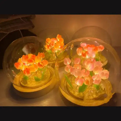 Artisanal tulip desk lamps glowing within glass domes, showcasing vibrant flowers and a warm, vintage aesthetic.