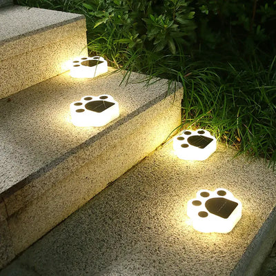 Solar LED paw print lights illuminating outdoor steps, providing decorative and functional lighting for landscape paths.