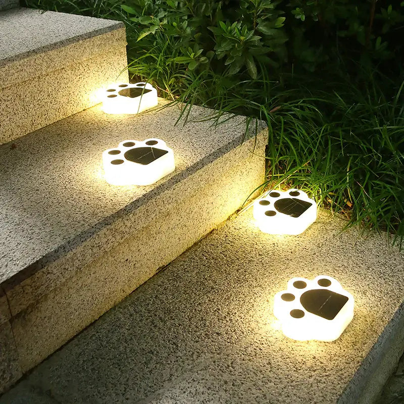 Solar LED ground lights shaped like paw prints illuminating outdoor stairs for a modern landscape.