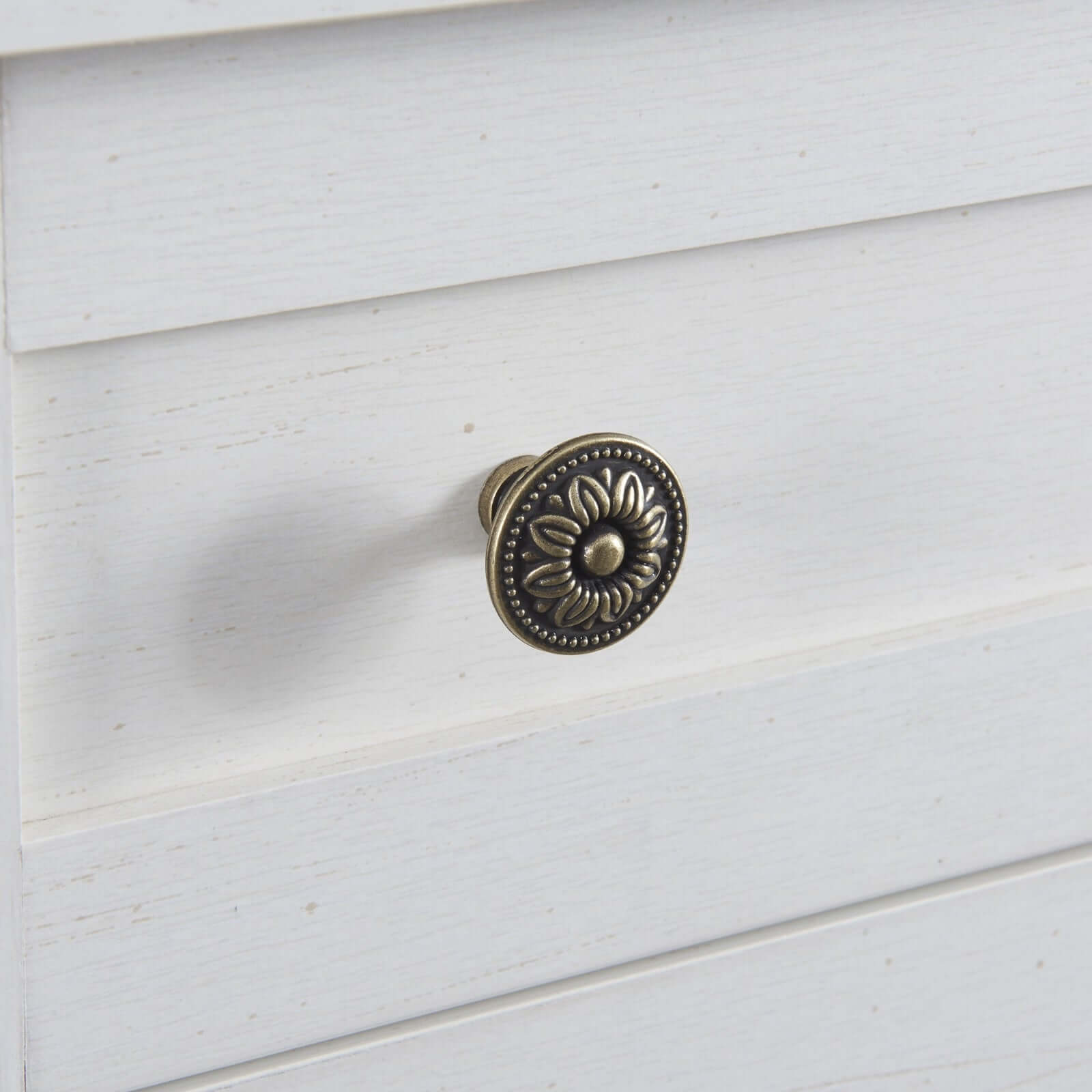 Antique white kitchen sideboard drawer knob with decorative floral design.