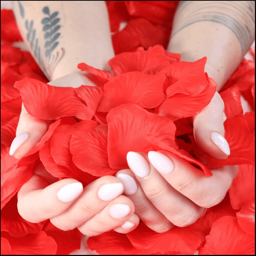 Hands holding lifelike red rose petals, perfect for romantic occasions and decor.