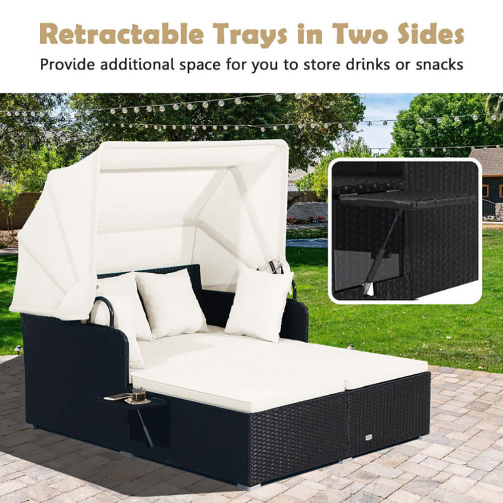 Patio rattan daybed with white retractable canopy and side trays for drinks or snacks in outdoor setting.