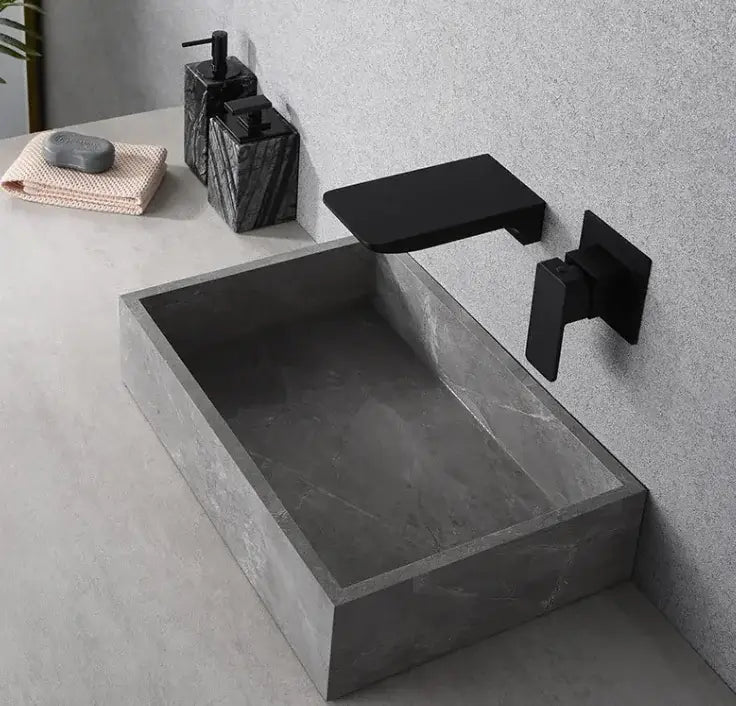 Modern black basin tap mounted on grey stone sink in stylish bathroom setting.