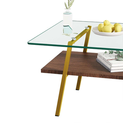 Rectangle coffee table featuring a tempered glass top, gold metal legs, and a wooden shelf with decorative items.