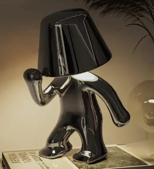 Elegant LED night lamp in black, stylish design resembling a figure, illuminating a bedside table.