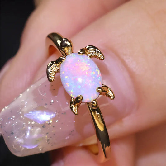 Round white opal turtle ring with gold accents, showcasing a sparkling opal gem, elegantly designed for women.