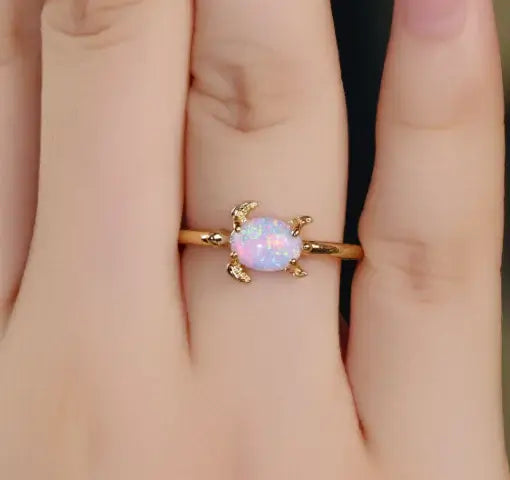 Beautiful round white opal turtle ring on a woman's finger, showcasing elegance and charm in gold metal.