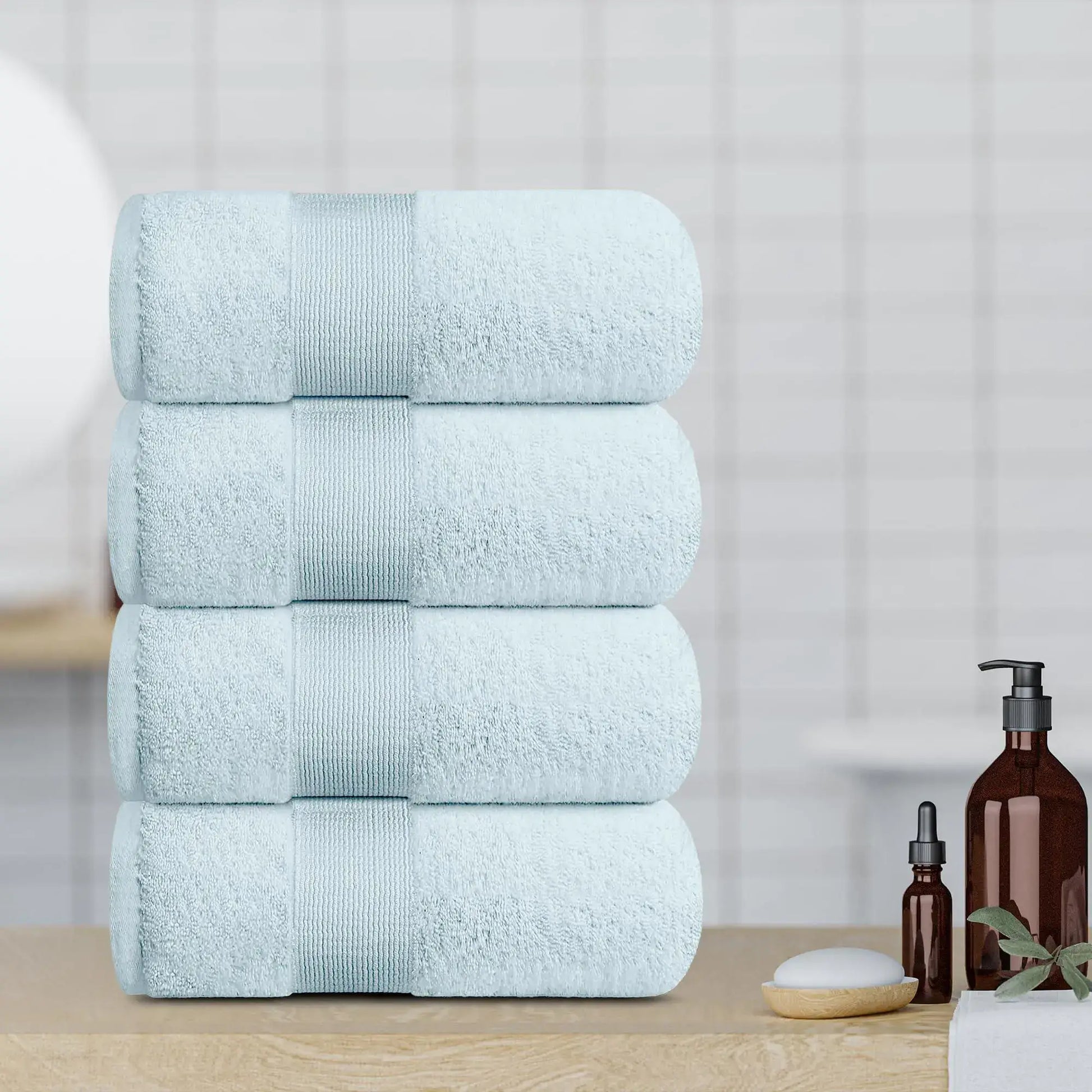 4 soft light blue bath towels stacked on a wood bathroom counter, perfect for a luxurious bathing experience.